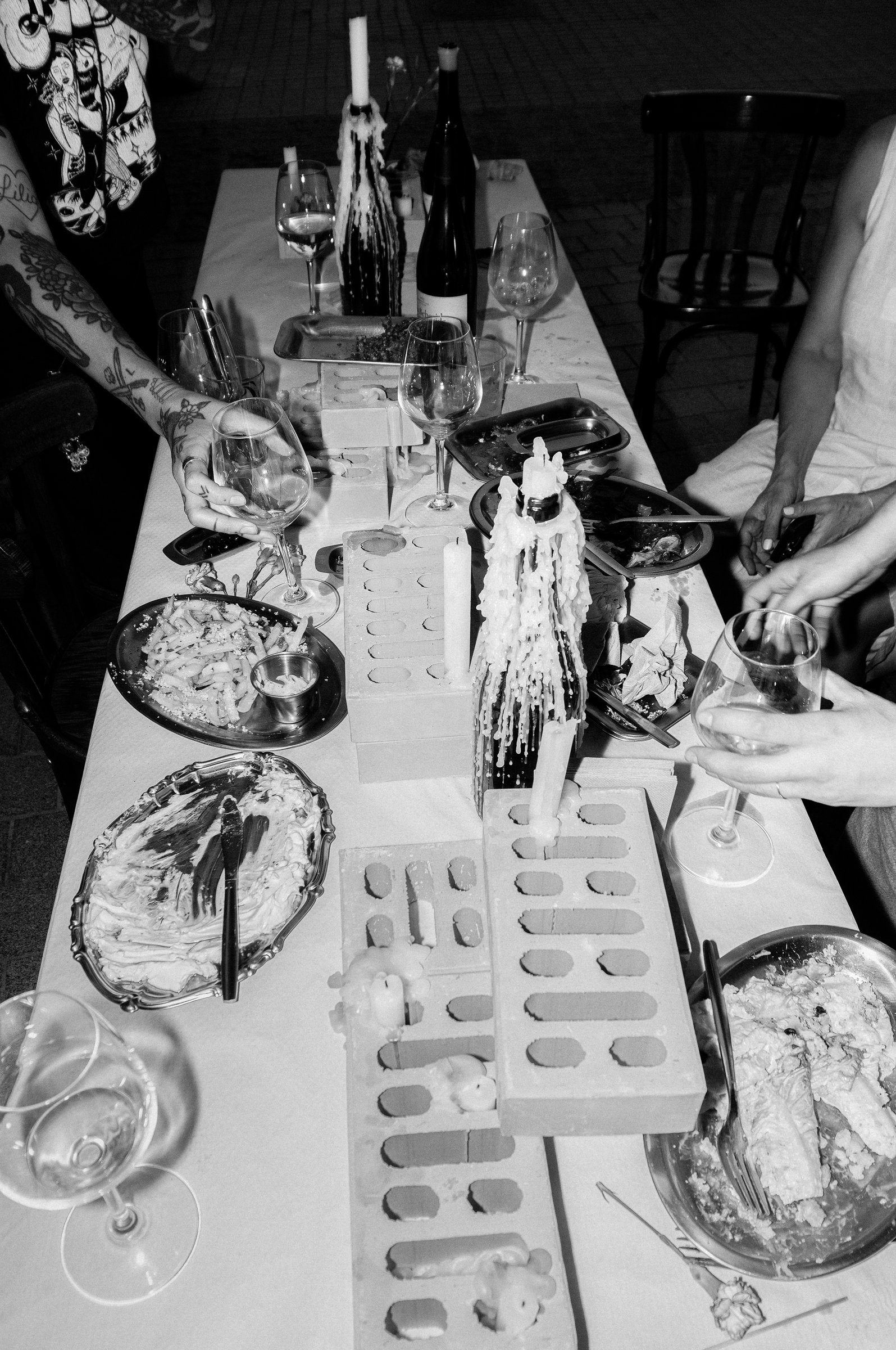 Mesa larga en blanco y negro con velas, copas y comensales